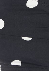 Zwarte stof met witte stippen, met een gladde textuur en een rekbaar ontwerp, geschikt voor zwemkleding of sportkleding.