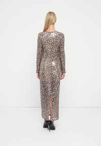Lang leopardmønstret kjole med paljetter, lange ermer og splitt bak. Farge: beige og brun med glitrende detaljer. Myk, gjennomsiktig tekstur.