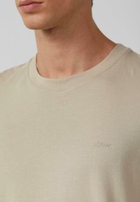 Beige t-shirt met korte mouwen, gemaakt van zachte stof en met een ronde hals. Voorzien van een subtiel s.Oliver-logo geborduurd op de borst.