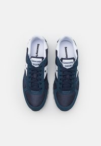 Mørkeblå Saucony Shadow joggesko har en overdel i mesh og semsket skinn med hvite detaljer, runde snøringer og en polstret krage for komfort.