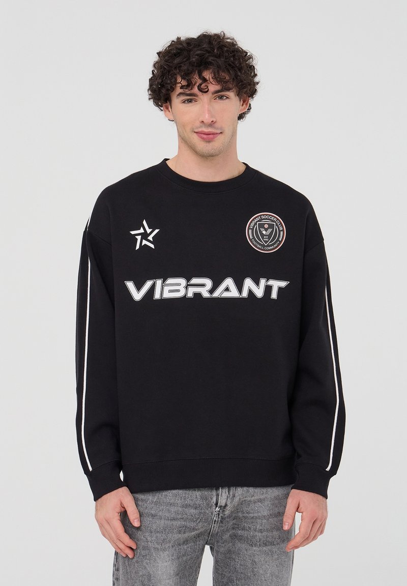 Felpa nera con collo rotondo, caratterizzata dalla scritta "VIBRANT" in grassetto bianco, un logo circolare e strisce bianche sui lati delle maniche.
