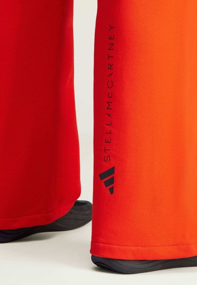 Pantaloni sportivi rossi con vestibilità ampia, caratterizzati da una stampa del logo nera sul lato e dettagli di colore a contrasto vicino all'orlo. Tessuto morbido.