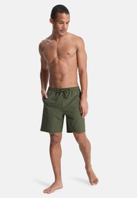 Πράσινο μαγιό σορτς από ελαφρύ ύφασμα, με ελαστική μέση και κορδόνι, μήκος έως το γόνατο και πλαϊνές τσέπες.