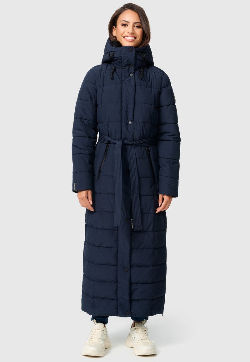Lång marinblå puffjacka med huva, bälte i midjan, ribbade detaljer, knappstängning fram och sidofickor. Har en quiltad design och slät textur.