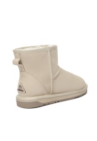 Beige suede ankle boot with soft fleece lining, rounded toe, and a pull tab on the back. Rubber outsole with logo detail.