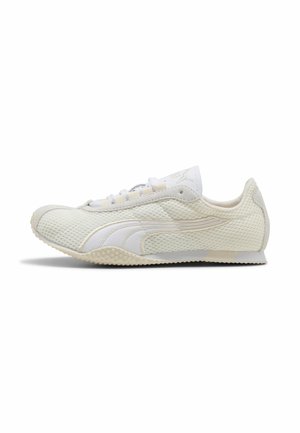 Wit sportief lage sneaker met gestructureerde mesh bovenkant, witte Puma-streep en licht gestructureerde rubberen zool, zijaanzicht op witte achtergrond.