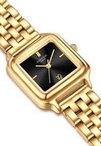 Zelta tonis taisnstūra pulkstenis ar melnu saules staru ciparnīcu, zeltītajiem stundu rādītājiem un metāla posmu aproci. Iekļauta korona regulēšanai.