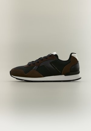Μαύρο και σκούρο καφέ sneaker χαμηλού προφίλ με λευκή σόλα και κορδόνια, με σήμανση Tommy Hilfiger στο πλάι και στην ταμπέλα της φτέρνας.