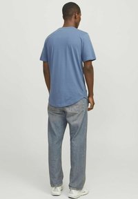 Blå bomulds T-shirt med rund halsudskæring og korte ærmer, parret med løstsiddende lyseblå jeans. Enkel design, ingen mønstre.