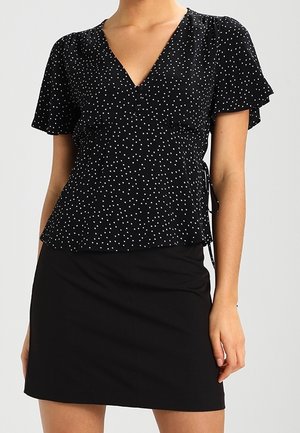 Černý zavinovací top s puntíky, krátkými volánkovými rukávy, výstřihem do V a staženým pasem, doplněný přiléhavou černou minisukní.