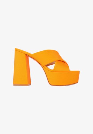 Mule plateforme orange vif avec un talon bloc épais et de larges brides croisées sur la zone des orteils.