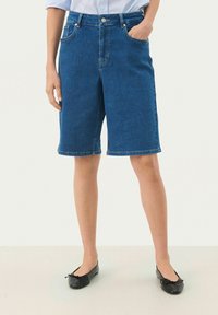 Denim bermudu šorti vidēji zila krāsā, ar augstu jostasvietu, priekšējām kabatām un taisnu griezumu, ar salocītiem apakšmalēm, lai nodrošinātu glītu apdari.