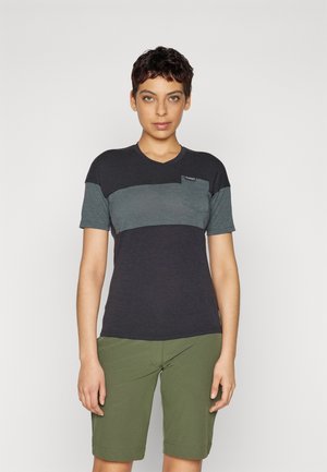 Kortsleeved t-skjorte i mørk blå og grå med v-hals, med en liten brystlomme og diskret merkevare, sammen med grønne shorts.