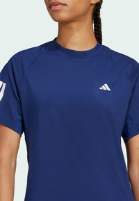 Camiseta deportiva de color marino con mangas cortas, cuello redondo y logo blanco en el lado izquierdo del pecho. Fabricada en tela que absorbe la humedad.