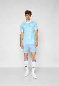 Jersey atlético de color azul claro con textura con patrón, acentos blancos, mangas cortas, combinado con pantalones cortos a juego y calcetines blancos a rayas.