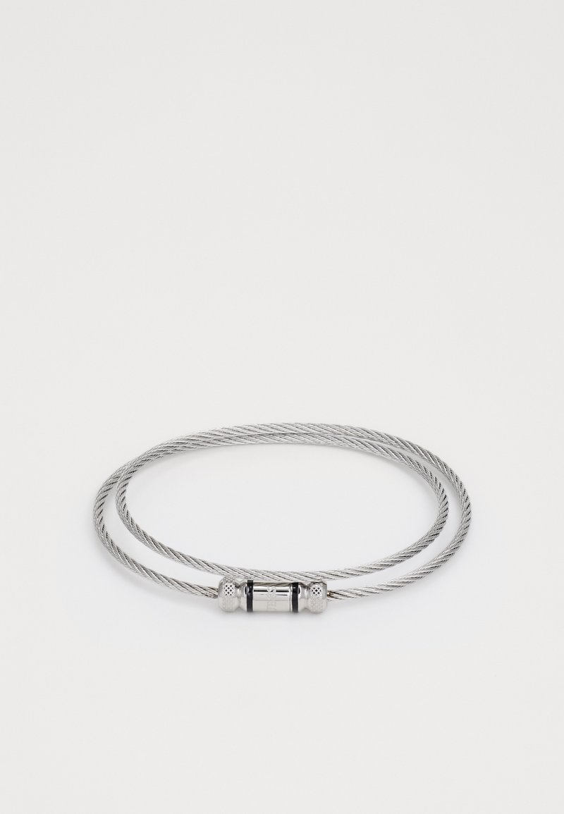 Silver kabelarmband med dubbelöglad design, svart central accent och texturerade metalldelar för säker fastsättning.
