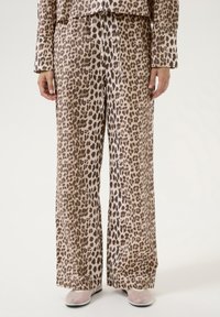 Leopardmønstrede bukser med brede ben lavet af blødt stof. Har elastisk talje med snøre og en afslappet pasform. Farvepaletten inkluderer beige og brune nuancer.