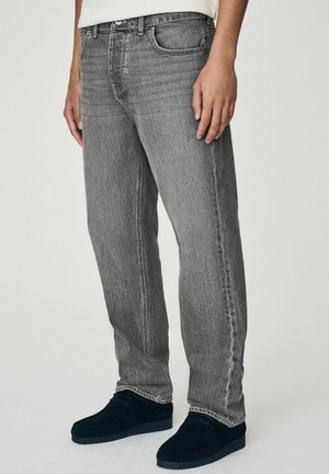 Grijze denim spijkerbroek met een rechte pasvorm, voorzien van een klassieke vijf-pocketontwerp, subtiele vervaging en zilverkleurige hardware. Draagt met zwarte suède schoenen.