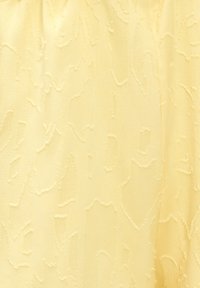 Tissu jaune pâle avec un motif subtil en relief de lignes et de formes tourbillonnantes irrégulières créant une surface texturée.