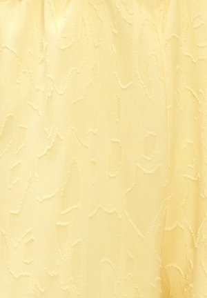 Tissu jaune pâle avec un motif subtil en relief de lignes et de formes tourbillonnantes irrégulières créant une surface texturée.