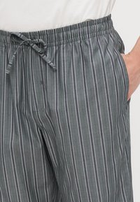 Grijze gestreepte broek met een elastische tailleband met trekkoord, lichtgewicht stof en zijzakken voor functionaliteit.