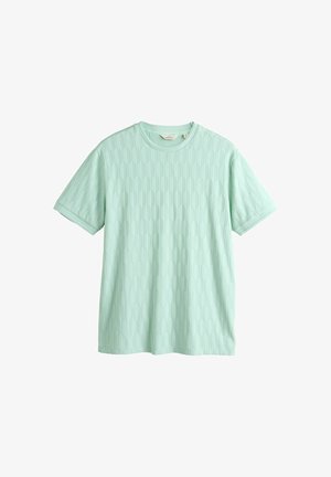 Világoszöld rövid ujjú póló, finom hatszögletű texturált mintával és kerek nyakkivágással.