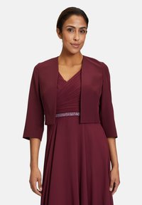 Bordeaux jurk met een geplooide lijfje en een korte boxy jasje. Bevat een aangesloten taille versierd met een sprankelende embellissement. Gladde stof.