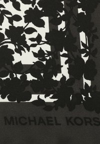 Motivo floreale nero su sfondo crema con il testo "MICHAEL KORS" in basso. Il tessuto ha un aspetto texturizzato e lavorato.