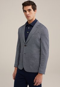Haringbone-gepatroniseerde blazer in marineblauw en wit, gemaakt van textuurstof, met een enkele knoopsluiting en twee voorkantzakken.