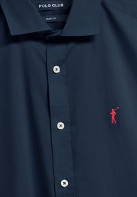 Slim fit ciemnoniebieska koszula z gładkiego materiału, z białymi guzikami i małym, haftowanym na czerwono wizerunkiem golfisty po lewej stronie klatki piersiowej.