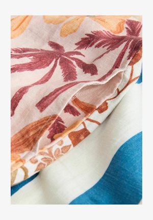 Audumi sakārtoti kā slāņi, attēlojot florālu rakstu rūsas un oranžas krāsās uz gaiša fona, kopā ar viendabīgiem ziliem un krēmkrāsas audumiem.