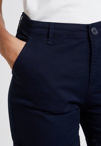 Laivastonsiniset puuvillahousut suorat lahkeet, sivutaskut, nappisuljenta ja teksturoitu vyötärönauha.