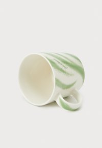 Κεραμική κούπα με λευκή βάση και ρίγες πράσινου χρώματος· διαθέτει κυρτή λαβή και είναι τοποθετημένη στο πλάι, δείχνοντας τις εσωτερικές λεπτομέρειες.