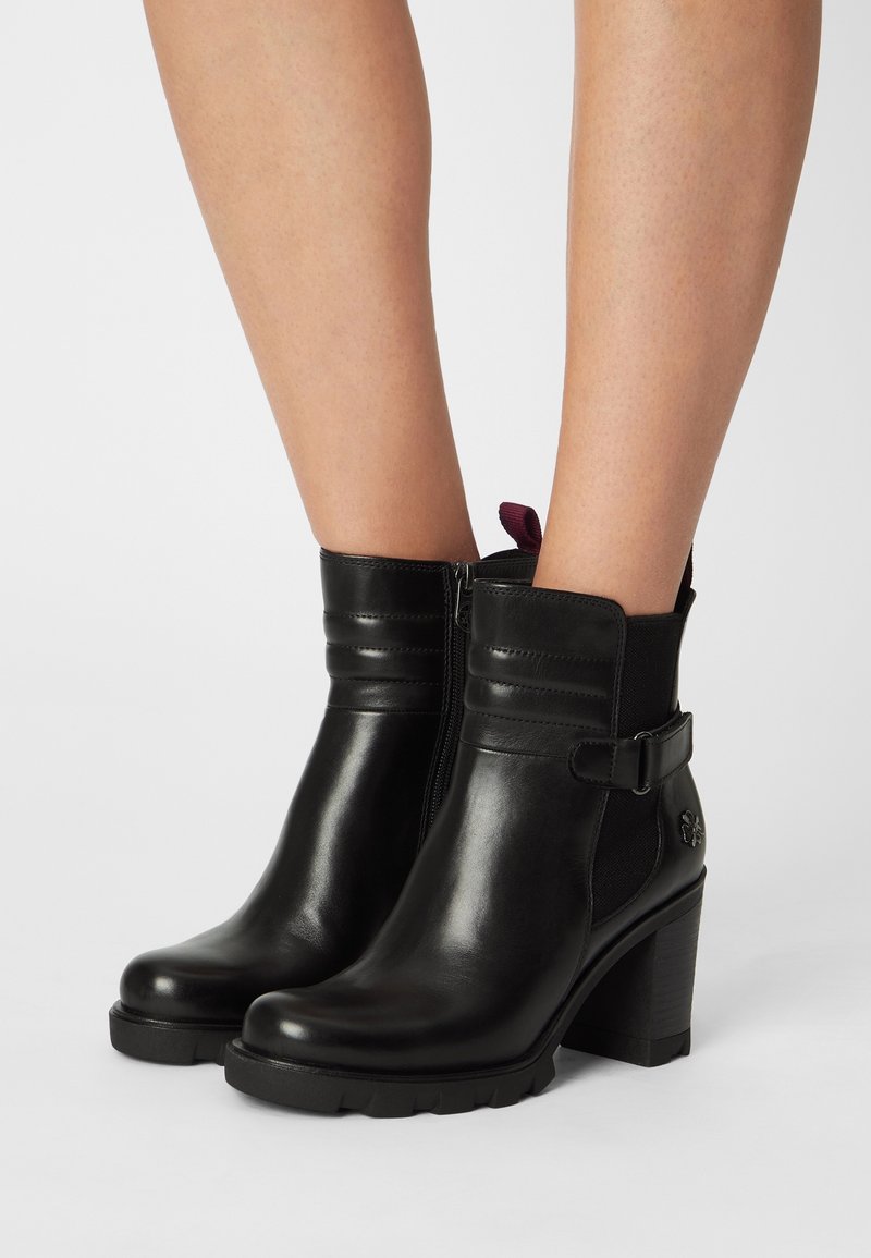 Bottines en cuir noir à finition lisse, fermeture éclair latérale, panneau texturé et talon épais. Dotées d'une sangle décorative et d'une boucle.