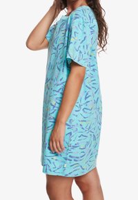 Une robe en coton turquoise légère avec une coupe ample, présentant un motif abstrait coloré de formes violettes et jaunes. Manches courtes.