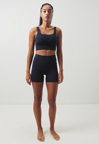 Fekete sportos crop top és magas derekú rövidnadrág, rugalmas anyagból készült, sima textúrával és egyszerű, testhezálló fazonnal.