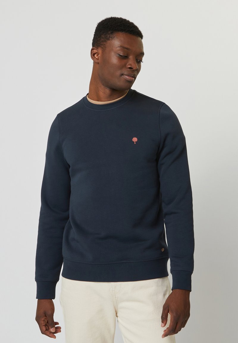 Felpa blu navy con scollo rotondo e maniche lunghe. Presenta un piccolo logo di un albero ricamato sul petto e un tessuto testurizzato.