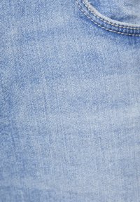 Svetle modrá džínová látka s mírnou texturou, obsahující viditelné švy a detail kapsy. Vzorec tkaní je rovnoměrný po celé ploše.