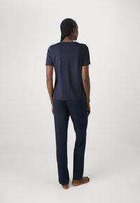 Top de manga corta de color azul marino y pantalones a juego en tela suave. El top tiene un escote redondeado; los pantalones son de pierna recta con una cinturilla elástica.