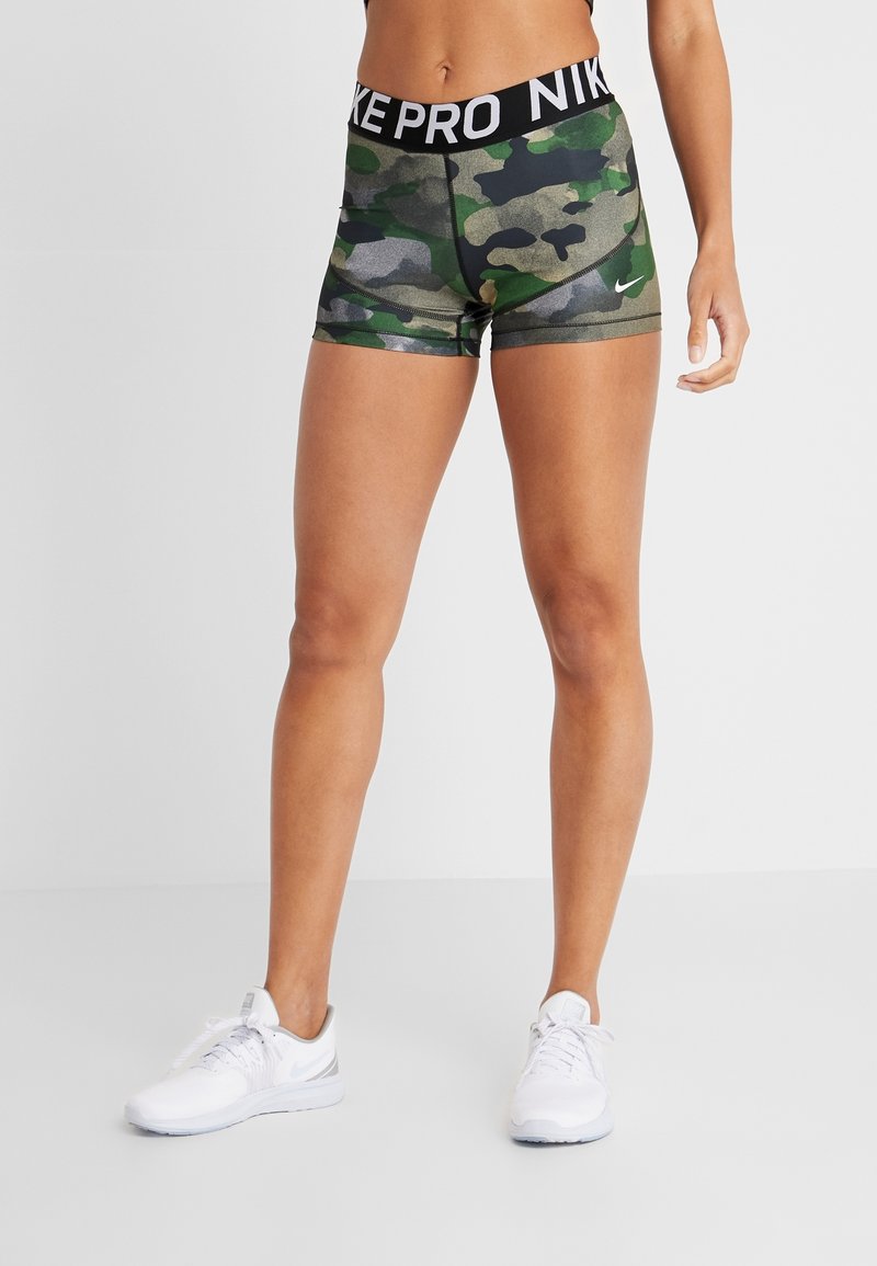 Nike Pro shorts in green camo pattern with black waistband, featuring "NIKE PRO" text and a small white logo on the lower left side.