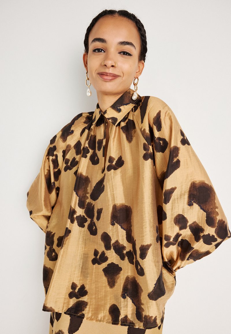 Satin blouse in goud met een zwart luipaardprintpatroon, met een hoge kraag en ballonsmouwen, een gladde textuur en een comfortabele pasvorm.
