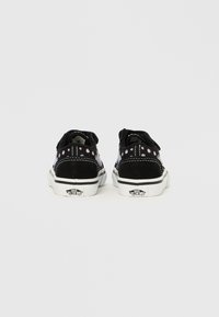 Scarpe in camoscio nero con suole in gomma bianca. Presentano dettagli floreali rosa e cuciture. Design a bassa altezza con forma classica e hardware minimalista.