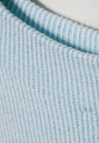 Ljust blått ribbat tyg med strukturerade linjer, som visar en mjuk och mysig framtoning. Materialet är tjockt och något ulligt.