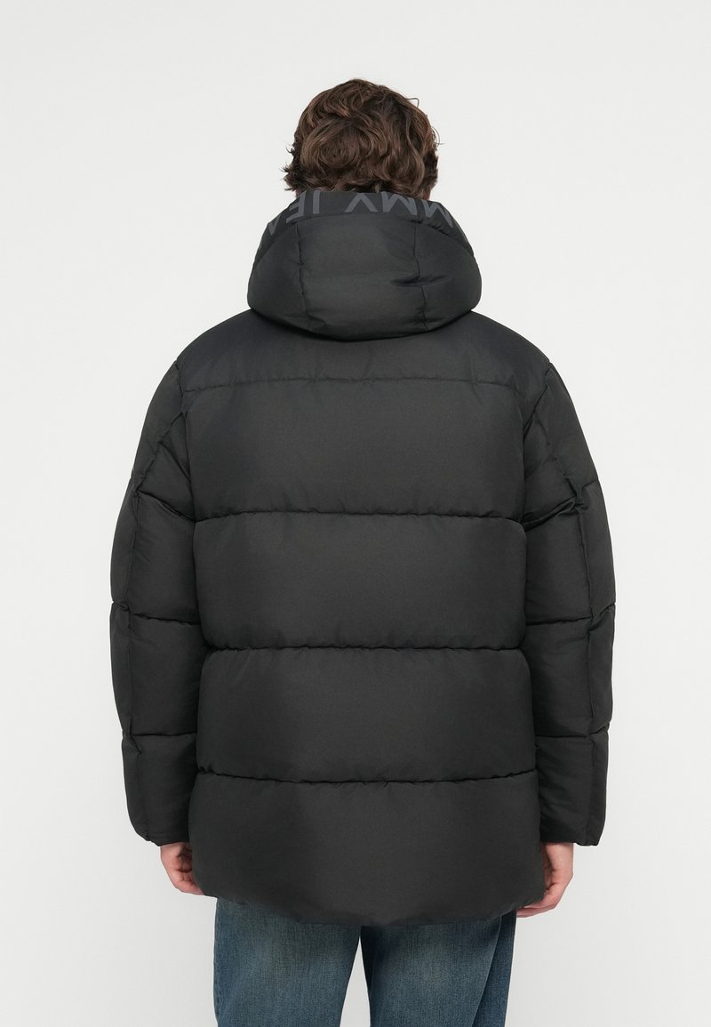 Schwarze Steppjacke mit Kapuze, mit einem gesteppten Muster, dickem Futter und einem Logo-Detail am Kragen. Leichter Stoff.