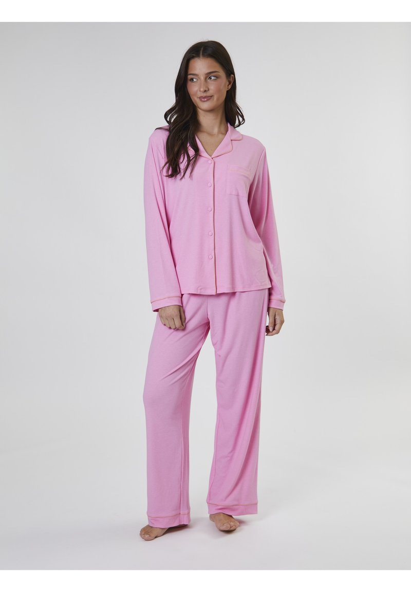 Conjunto de pijama de color rosa claro que consiste en una parte superior con botones y un bolsillo, y pantalones largos, hecho de una tela suave con una textura lisa.