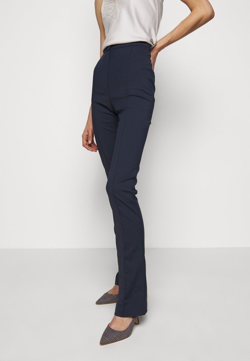 Marineblauwe high-waisted broek met een tailored fit, gemaakt van gladde stof. Heeft een slanke silhoutte, zijzakken en een klassiek, strak ontwerp.