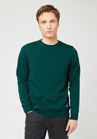 Groene crewneck sweatshirt van katoen met geribde manchetten. Heeft een klein zwart boomlogo op de borst en een ronde zoom.