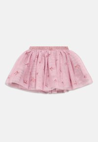 Růžová tylová sukně s třpytivým pasem a malými vyšitými červenými mašlemi rozptýlenými po látce, rozšířený a vrstvený design.