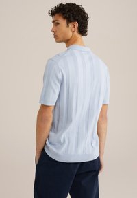 Polo shirt azzurro chiaro a maniche corte con una texture a coste e sottili righe verticali, dotato di un colletto classico e orlo dritto.