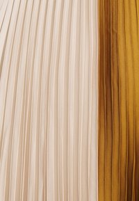 Pionowe plisowane tkaniny z sekcjami w kremowym, musztardowożółtym i brązowym atłasowym wykończeniu.